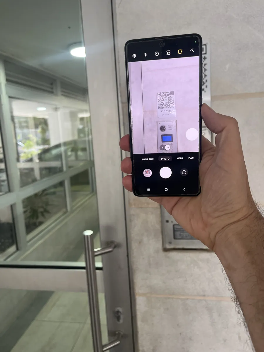 A phone held up to the entrance, scanning the QR plate